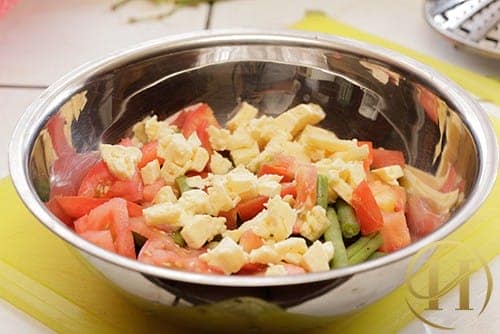 Bước 2: Để đậu nguội bớt rồi cho vào trong một cái bát to. Sau đó, cà chua, hành tây được rửa sạch, thái kiểu hạt lựu và cho vào bát cùng với 1 ít phô mai