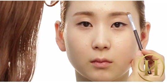 Bước 5: Sau bước so sánh trên, nếu 1 bên lông mày bị thấp hơn, lại lặp bước dùng cọ nhỏ và phấn mắt cùng màu tóc để kẻ và "nâng" lông mày bên thấp hơn bằng bên còn lại.